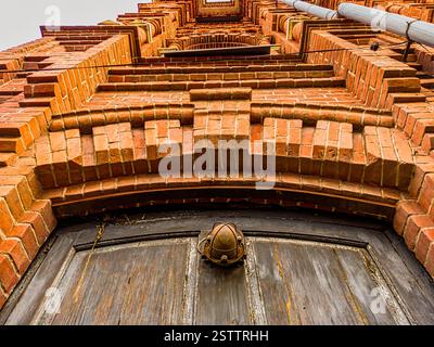 Regardez d'en bas un vieux bâtiment en briques avec un fragment de porte en bois au premier plan Banque D'Images