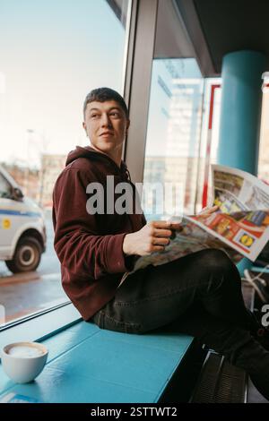 Portrait d'un homme assis dans un café, lisant des journaux et buvant du café Banque D'Images