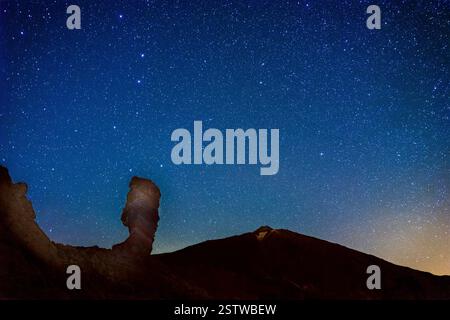 Le ciel nocturne et le volcan Teide en arrière-plan. Le rocher Roques de Garcia au premier plan. Banque D'Images