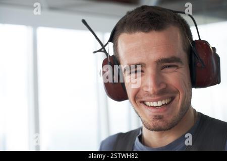 Sourire, écouteurs et portrait de l'homme à l'aéroport pour le contrôleur aérien, la communication de tour et la sécurité. Technicien aéronautique, exploitant de vol et Banque D'Images