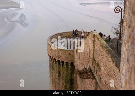 Mont Saint-Michel, France - 25 janvier 2016 : les touristes apprécient la vue panoramique depuis les anciennes fortifications en pierre surplombant les marées. Banque D'Images