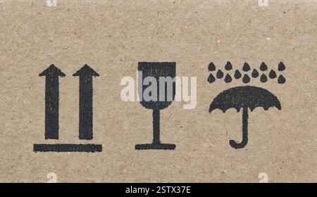 Les étiquettes d'avertissement sur la silhouette de la boîte en carton forment des flèches en verre de parapluie, cette façon vers le haut fragile garder sec instructions logistiques de transport. Banque D'Images