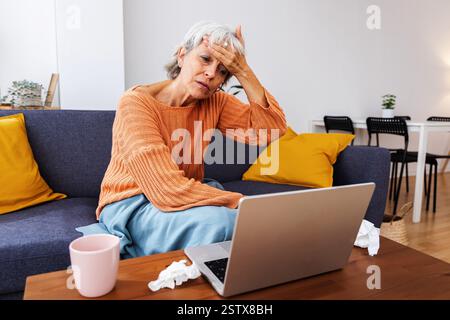 Femme malade senior ayant un appel vidéo avec le médecin de la maison Banque D'Images