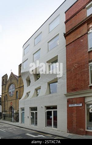 The Scoop, un nouvel immeuble de bureaux sur O'Meara Street, Londres, Royaume-Uni. Bâtiment en briques blanches avec une pelle distinctive pour protéger la vue de la rosace de l'église. Banque D'Images