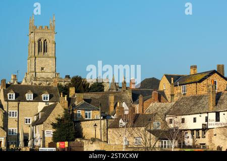 Rassemblez Michaels Church et attrayants vieux bâtiments en pierre et toits sur une journée ensoleillée de février avec un ciel bleu clair, Stamford, Lincolnshire, Angleterre, Royaume-Uni Banque D'Images