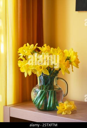 Étonnant bouquet de fleurs de jonquille jaunes dans une cruche en verre pour la décoration intérieure. Style vintage. Décoration maison pour Pâques ou fête des mères. Copier l'espace. Banque D'Images