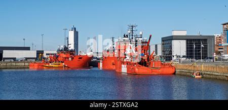 Des navires rouge vif sont vus amarrés dans un cadre portuaire organisé et industriel, mettant en valeur le transport maritime et les activités industrielles sous un bleu clair Banque D'Images