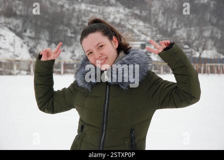 Joie d'hiver dans la nature avec femme souriante en manteau vert. Banque D'Images