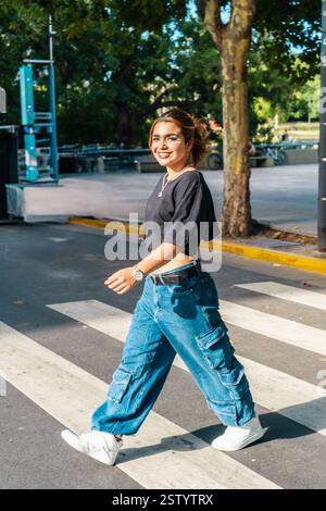 Femme souriante traversant la rue en tenue décontractée Banque D'Images