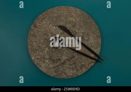 Vue de dessus de la plaque de marbre brun, couverts noirs sur fond vert foncé. Présentation des aliments, plateau en pierre. Espace de copie, pose à plat. Banque D'Images