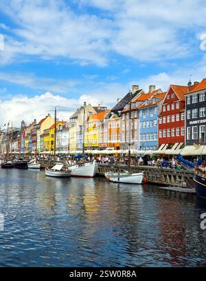 Front de mer dynamique à Copenhague avec des maisons colorées et des bateaux sous un ciel bleu lumineux Banque D'Images