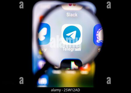 Munich, Allemagne. 19 février 2025. Le logo de l’application Telegram est visible à travers une loupe sur l’écran d’un smartphone le 19 février 2025. Telegram est un service de messagerie instantanée gratuit du développeur Telegram FZ-LLC pour une utilisation sur smartphones, tablettes, smartwatches et PC, qui a été développé en Russie. Par défaut, les chats ne sont cryptés qu'entre le client et le serveur ; les chats entre deux personnes peuvent éventuellement être cryptés de bout en bout en tant que « chats secrets ». Crédit : Matthias Balk/dpa/Alamy Live News Banque D'Images