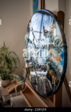 Élégante grande horloge murale en résine époxy faite dans des tons bleus, dorés, bruns avec des motifs nautiques Banque D'Images