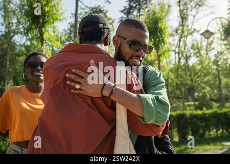 Des amis afro-américains joyeux s'embrassant dans la rue à l'extérieur, saluant, disant au revoir ou bonjour. Banque D'Images