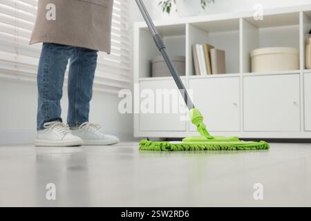 Femme nettoyant le sol avec une serpillière en microfibre à l'intérieur, gros plan Banque D'Images