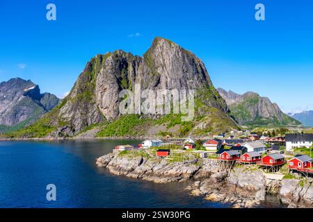 Vue sur la côte des îles Lofoten en Norvège avec montagnes et cabines rouges traditionnelles Banque D'Images