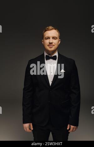 Un bel homme dans un smoking sur mesure respire la confiance et le charme dans un studio. Banque D'Images