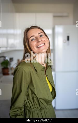 Portrait heureuse femme blonde souriante regardant la caméra debout à la maison ayant la bonne humeur profiter du temps. Banque D'Images