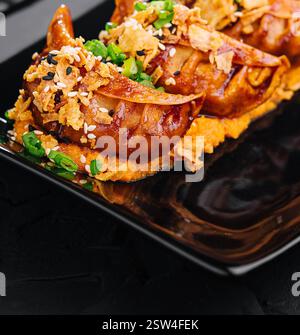 Boulettes frites Gyoza sur assiette noire Banque D'Images