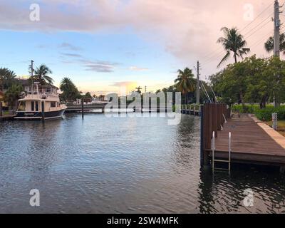 Une marina sereine au bord de l'eau au coucher du soleil, avec des yachts de luxe et des voiliers amarrés le long des eaux calmes. Banque D'Images