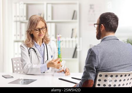 Patient masculin au rendez-vous avec un orthopédiste regardant un modèle de colonne vertébrale humaine Banque D'Images