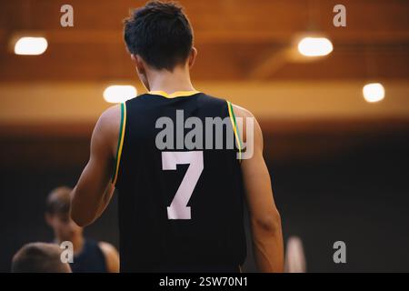 Joueur de basket-ball junior dans un match de basket-ball. Jeune joueur de basket-ball dans un top noir avec le numéro sept. Séance d'entraînement de basket-ball pour vous Banque D'Images