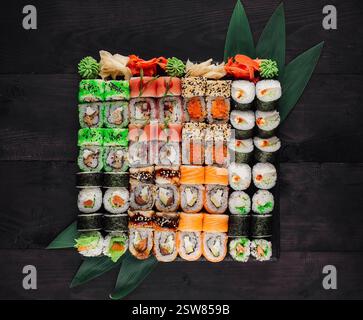 Grand ensemble de sushi avec une variété de rouleaux servis sur fond de table en bois noir Banque D'Images