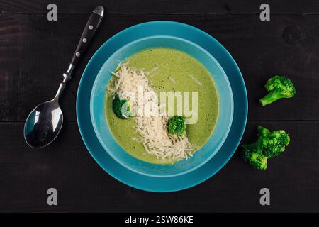 Soupe à la crème de brocoli servie dans un bol bleu posé sur une table en bois rustique Banque D'Images