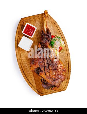 Jarret d'agneau rôti avec légumes et sauces sur planche de bois Banque D'Images