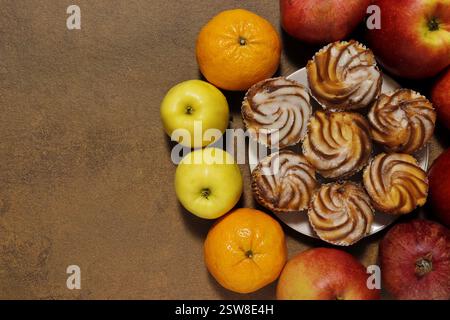 Gros plan de gâteaux sur une soucoupe entourée de fruits - pommes, oranges, grenades. Vue de dessus. Banque D'Images