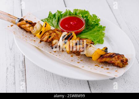 Poulet grillé shish kebab servi sur pain pita avec sauce tomate et laitue Banque D'Images