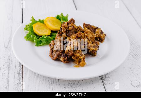 Délicieux ragoût de bœuf avec pommes de terre et oignons couchés sur une plaque blanche sur fond blanc Banque D'Images
