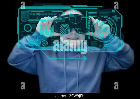 Fille en sweat à capuche bleu avec casque de réalité virtuelle utilisant l'interface virtuelle HUD sur fond noir. Lunettes de réalité virtuelle. Cyberespace, divertissement Banque D'Images
