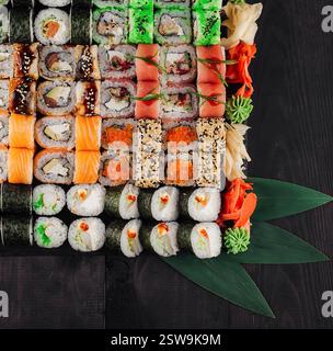 Grand ensemble de sushi avec une variété de rouleaux servis sur fond de table en bois noir Banque D'Images