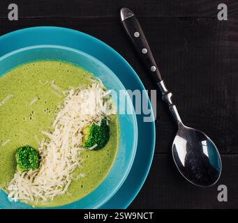 Soupe à la crème de brocoli servie dans un bol bleu posé sur une table en bois rustique Banque D'Images