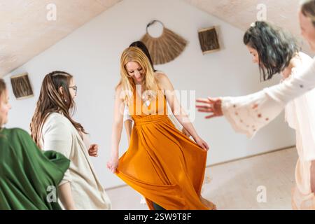 Groupe de femmes joyeuses de tous âges, des gens heureux dansant ensemble portant des robes colorées traditionnelles et des vêtements hippy. Personnes libres appréciant les activités de loisirs, en mettant l'accent sur l'amitié, le plaisir, le mouvement. Banque D'Images