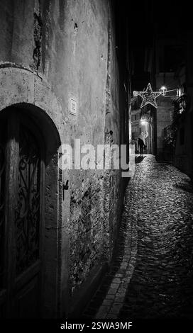 Un village italien déserté par une froide nuit d'hiver, où le temps semble s'arrêter sous la lueur tamisée des anciens lampadaires Banque D'Images