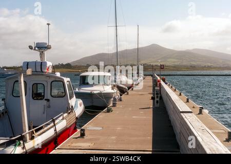 Un quai avec plusieurs bateaux amarrés au bout de celui-ci. La jetée est entourée d'eau et de montagnes en arrière-plan Banque D'Images