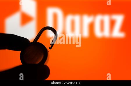 Dhaka, Bangladesh- 15 novembre 2024 : une main tient un cadenas déverrouillé devant le logo Daraz. Banque D'Images