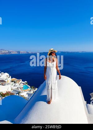Une femme en robe blanche profite de la vue imprenable sur Santorin sous le ciel bleu vif Banque D'Images