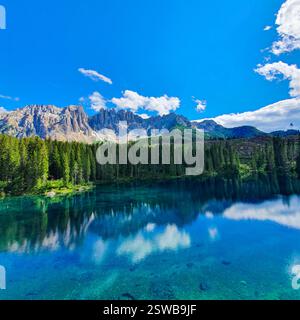 Lac de montagne à couper le souffle reflétant le ciel bleu entre des sommets imposants et des forêts verdoyantes Banque D'Images
