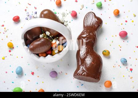 Lapin de Pâques au chocolat avec panier et œufs sur fond blanc Banque D'Images
