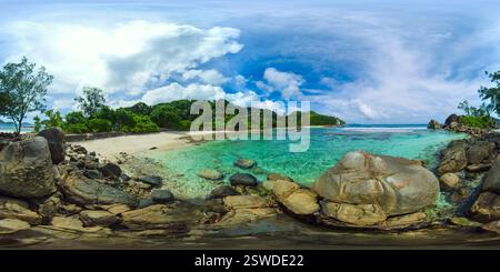 Des eaux cristallines entourent des rochers lisses sur une petite plage, avec un fond de verdure sous un ciel lumineux. Lagon de Port Glaud. Seychelles. VR 360. Banque D'Images