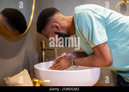 Fatigué endormi Afro-américain gars se lavant le visage avec de l'eau le matin Banque D'Images