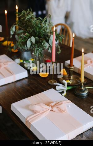 Une table magnifiquement agencée présente des coffrets cadeaux, des bougies colorées et de la verdure fraîche pour une atmosphère festive. Banque D'Images