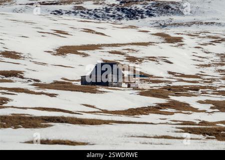 Cabane de montagne éloignée par un lac gelé. Banque D'Images