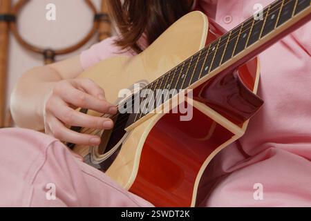 Gros plan de femme guitariste, exécutant le style strumming de guitare classique acoustique, en utilisant un instrument acoustique à six cordes. Jeune femme portant pi Banque D'Images