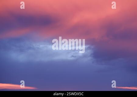 Les teintes pastel du coucher de soleil peignent le ciel avec de doux nuages roses et violets Banque D'Images
