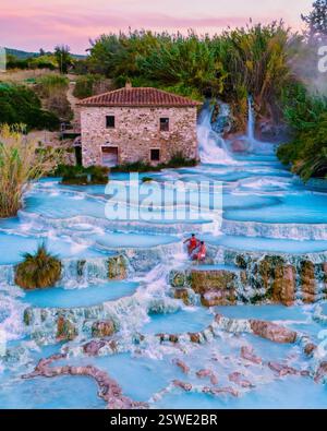 Détente dans les sources thermales naturelles de Saturnia sous un coucher de soleil vibrant en Toscane Banque D'Images
