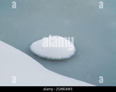Mise au point sélective. Glace de printemps, petite île ronde enneigée sur glace fondante. Fond naturel abstrait. Banque D'Images